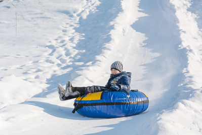 boy snow tubing down a hill